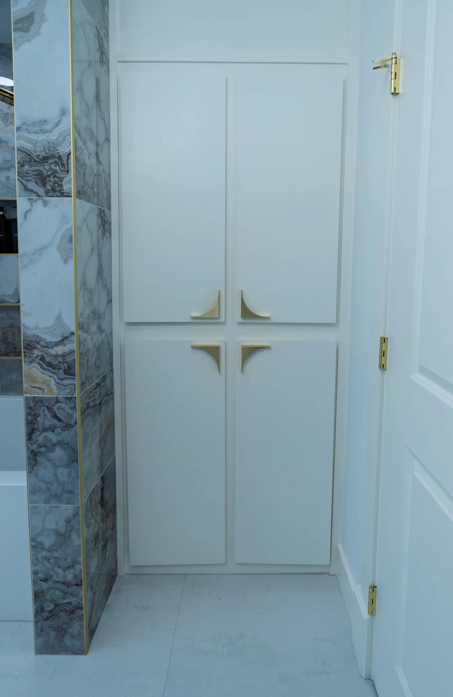 Custom bathroom linen closet with brass hardware and marble tile, Portland OR